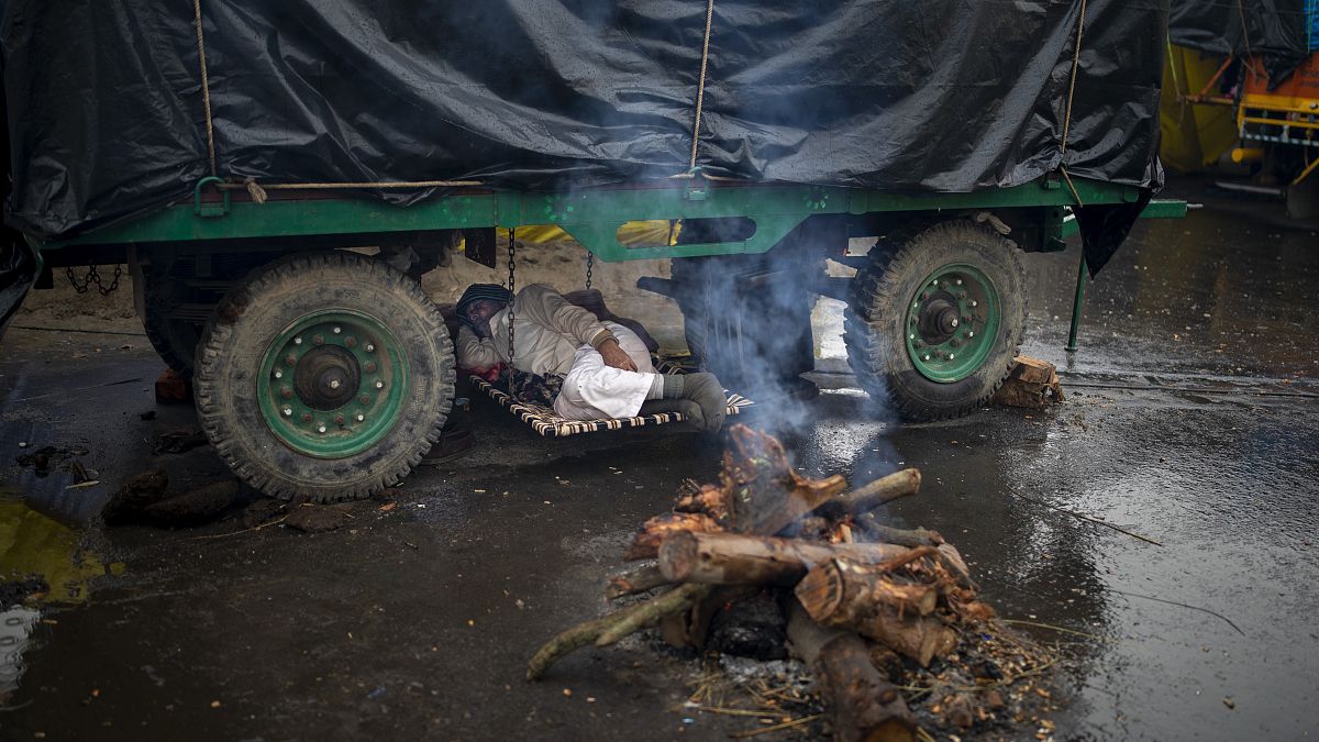 Un contadino si riposa sotto al suo trattore al confine tra gli Stati di Delhi e Uttar Pradesh, in India, lunedì 4 gennaio 2021