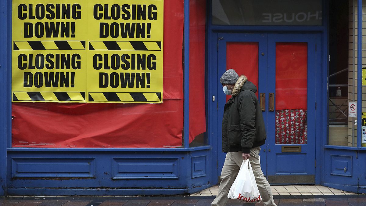 Una persona pasa ante una tienda cerrada en Escocia