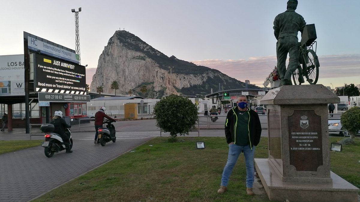 El español Alfredo Valencia junto a la estatua a los trabajadores transfronterizos en la frontera entre España y Gibraltar.