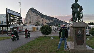 El español Alfredo Valencia junto a la estatua a los trabajadores transfronterizos en la frontera entre España y Gibraltar.