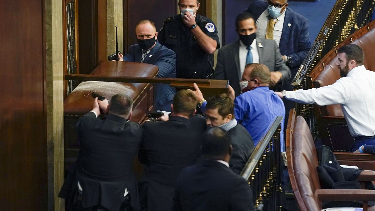 U.S. Capitol Police with guns drawn stand near a barricaded door as protesters try to break into the House Chamber at the U.S. Capitol on Wednesday, Jan. 6, 2021.