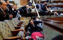 La gente se refugia en la galería de la Cámara de Representantes mientras los manifestantes tratan de entrar en la Cámara de Representantes en el Capitolio de EE.UU.