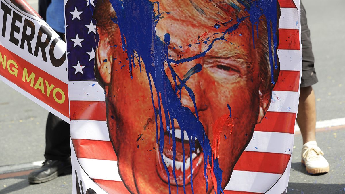An image of U.S. President Donald Trump is splashed with paint by protesters as they hold a rally opposing the recent attack of the U.S. against Iran, where it killed Soleiman