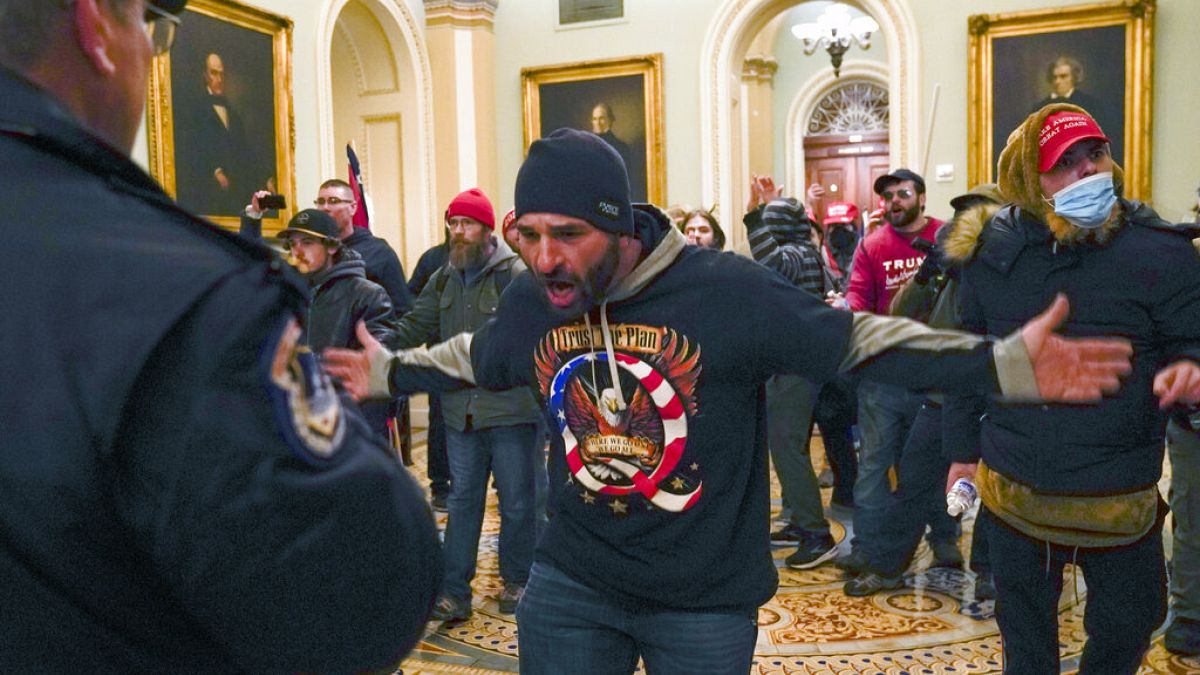 Trump supporters gesture to U.S. Capitol Police in the hallway outside of the Senate chamber at the Capitol in Washington, Wednesday, Jan. 6, 2021.