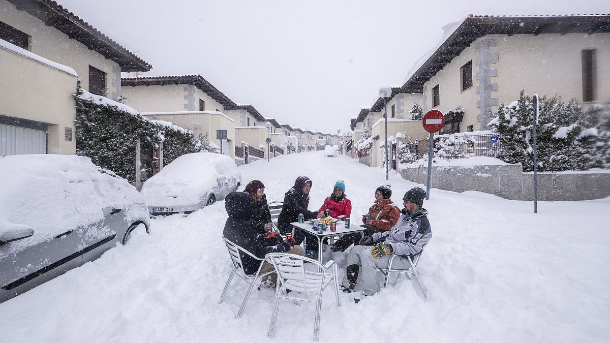Unos vecinos beben en medio de la calle durante una fuerte nevada en Bustarviejo, en las afueras de Madrid, España, el  9 de enero de 2021.