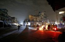 People are silhouetted on vehicles headlights on a dark street during widespread power outages in Rawalpindi, Pakistan, Sunday, Jan. 10, 2021.