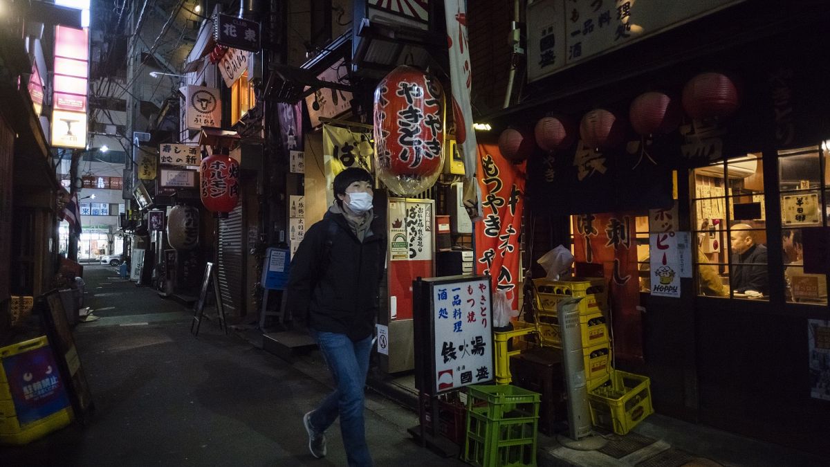A man walks through an alley filled with restaurants and bars after 8 p.m. on the first day of a coronavirus state of emergency in Tokyo on Friday, Jan. 8, 2021.