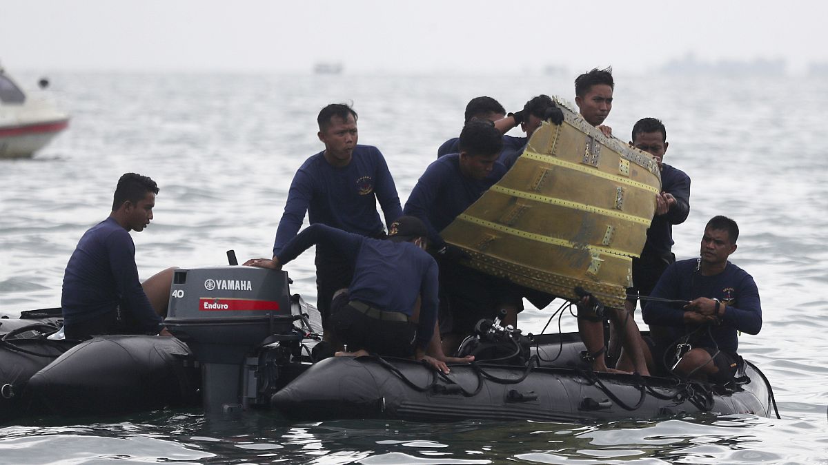 Indonesian Navy divers pull out a part of an airplane out of the water during a search operation for the Sriwijaya Air passenger jet that crashed into the sea near Jakarta