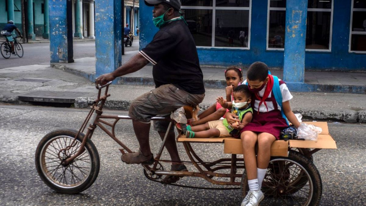 Un hombre lleva a tres niños en su triciclo en La Habana, Cuba