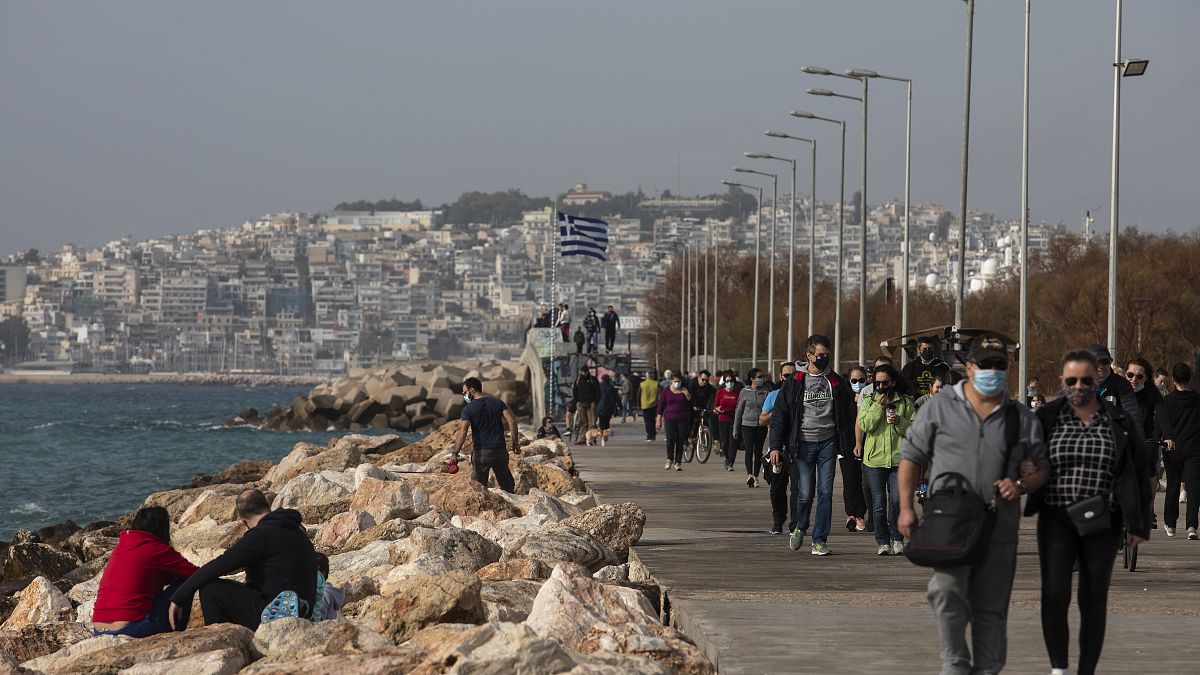 People walk on a promenade at Alimos suburb, south of Athens, Sunday, Jan. 10, 2021. 