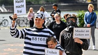 An anti-lockdown protester in a prison suit holds a sign reading "mask sets you free" at a demonstration against restrictions in Cologne, Germany, May 23, 2020.