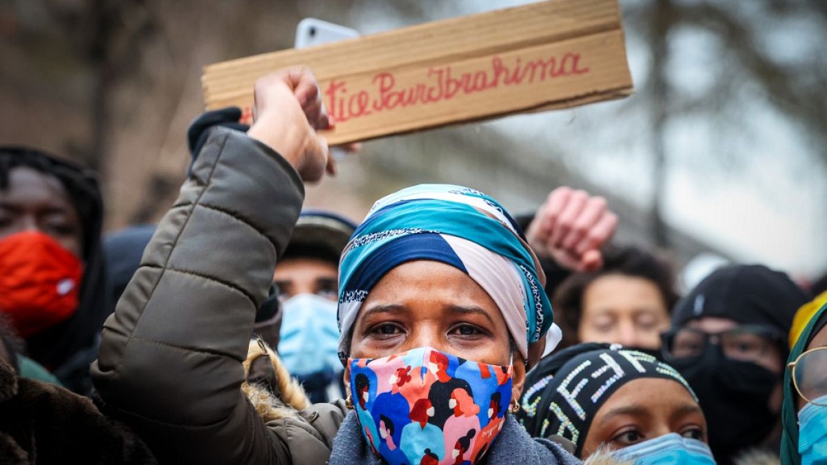 IB's mother takes part in a demonstration on January 13, 2021, outside the police station in Brussels where her son was held