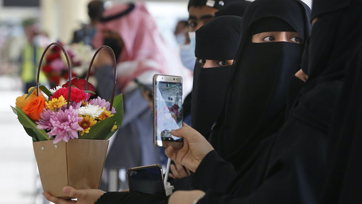 Saudi women hold flowers as they wait for the arrival of their Qatari relatives on the first Qatar Airways plane in three years to land at King Khalid Airport in Riyadh