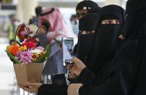 Saudi women hold flowers as they wait for the arrival of their Qatari relatives on the first Qatar Airways plane in three years to land at King Khalid Airport in Riyadh