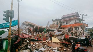 Residents inspect earthquake-damaged buildings in Mamuju, West Sulawesi, Indonesia, Friday, Jan. 15