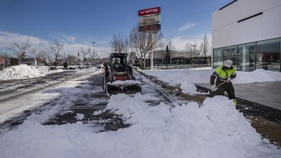 Workers remove snow at a parking lot in Alcobendas, outskirts of Madrid, Spain, Friday, Jan. 15, 2021.(AP Photo/Bernat Armangue)