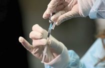 A medical worker holding a Pfizer-BioNTech vaccine and a syringe during mass vaccination starts in Vienna, Austria, Friday, Jan. 15, 2021. 