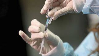 A medical worker holding a Pfizer-BioNTech vaccine and a syringe during mass vaccination starts in Vienna, Austria, Friday, Jan. 15, 2021.