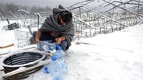 Un migrant utilise des bouteilles en plastique pour récupérer de l'eau, le 11 janvier 2021, dans le camp de Lipa, Bosnie