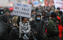 Paris'te gösterilere katılan bir vatandaş. Taşıdığı parnkatta "Videoları istiyoruz" yazıyor.