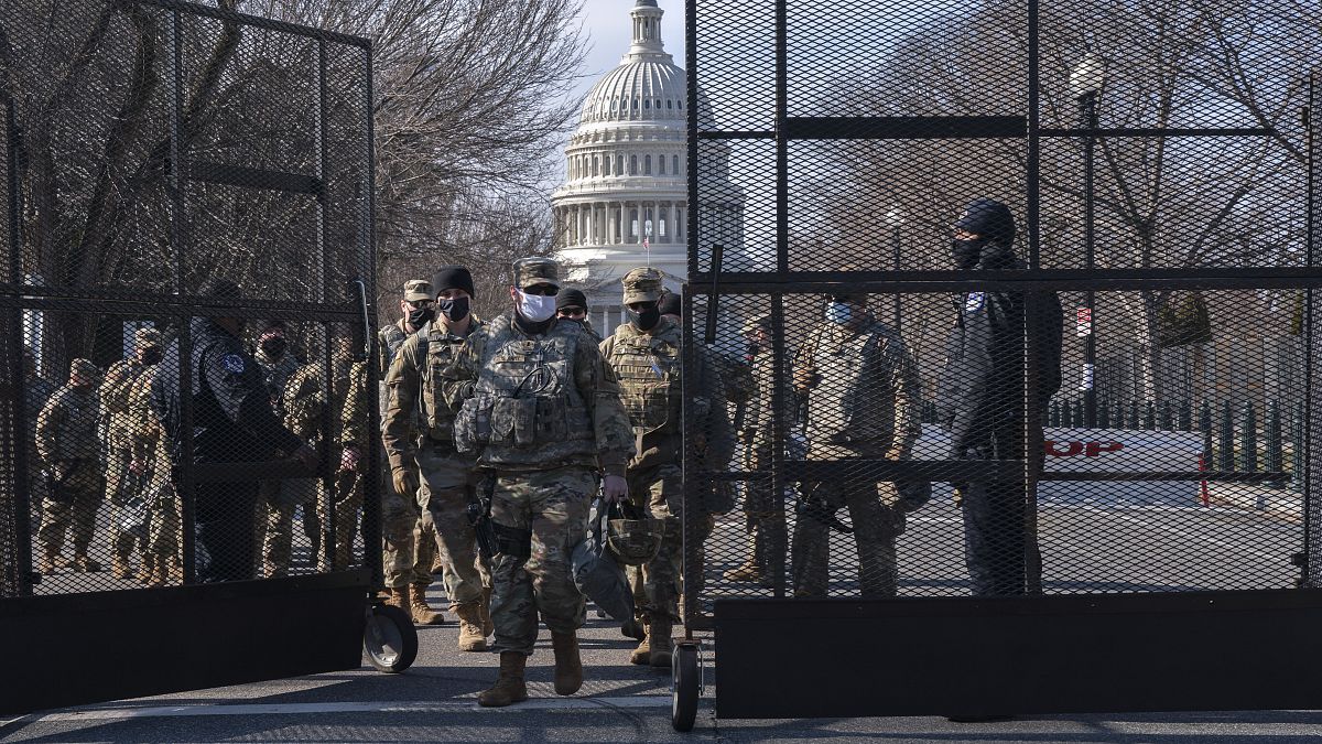 Members of the National Guard change shifts as they exit through anti-scaling security fencing on Saturday, Jan. 16, 2021, in Washington.