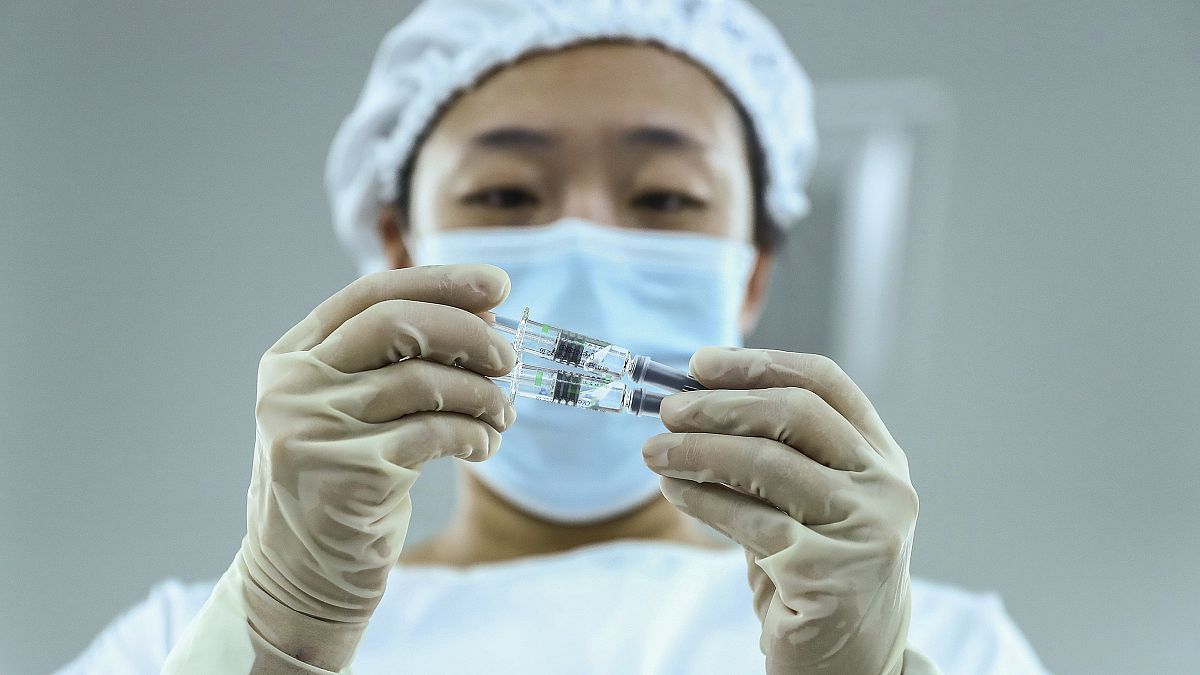 Kínai egészségügyi dolgozó nézi a Sinopharm vakcinájával