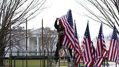 A worker installs America flags outside the White House ahead of President-elect Joe Biden's inauguration ceremony, Jan. 18, 2021, in Washington. 