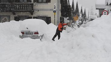 A man shovels his car free of snow after days of snowfall in Garmisch-Partenkirchen, southern Germany, Monday, Jan. 18, 2021. 
