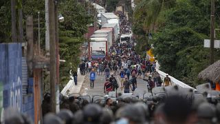 Honduran migrants, top, confront Guatemalan soldiers and police manning a roadblock on the highway in Vado Hondo, Guatemala, Monday, Jan. 18, 2021.
