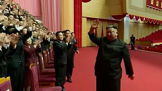 Kim Jong Un in front of the group of senior officials described by the state media as "the central governing body of the party" applauding and cheering.