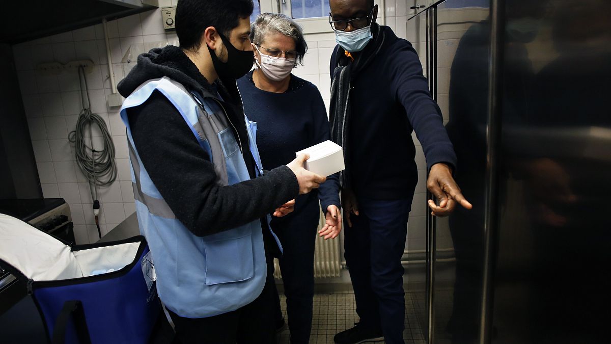 Medical delivery man Raphaël Abi Khalil, left, gives box of vaccine vials of Pfizer-BioNTech vaccination against COVID-19,
