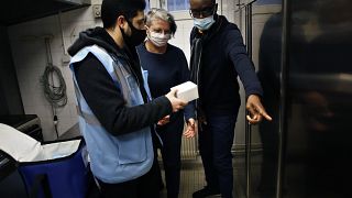 Medical delivery man Raphaël Abi Khalil, left, gives box of vaccine vials of Pfizer-BioNTech vaccination against COVID-19,