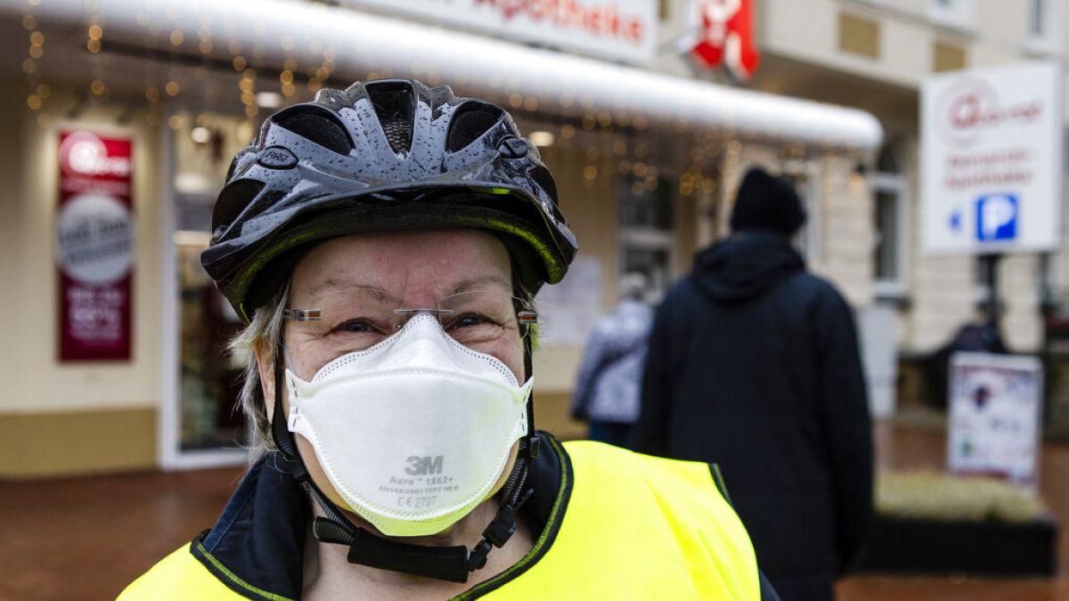 A woman with a FFP2 mask stands in front of a pharmacy in Kiel, northern Germany, Tuesday, Dec. 15, 2020