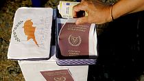 A demonstrator takes a mock copy of Cyprus passport during a demonstration against corruption outside of the conference center in the capital Nicosia, Cyprus, Oct. 14, 2020.