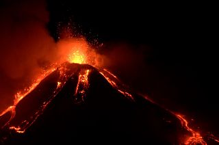 Mount Etna with explosions at top and lava streaming down the sides