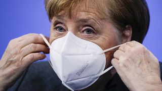 German Chancellor Angela Merkel puts on a face mask after a news conference on further coronavirus measures, at the Chancellery in Berlin, Germany, Jan. 19, 2021.