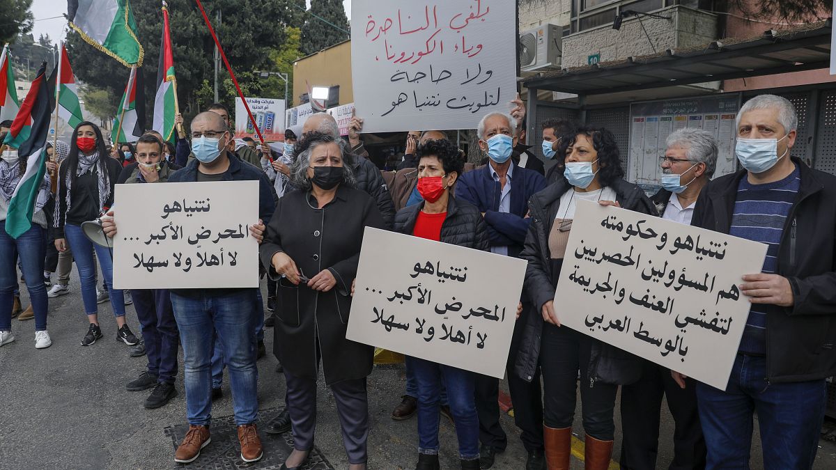 عرب إسرائيليون يرفعون لافتات وأعلام فلسطينية خلال مظاهرة ضد رئيس الوزراء الإسرائيلي بنيامين نتنياهو أثناء زيارته للناصرة