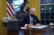 President Joe Biden signs his first executive orders in the Oval Office of the White House