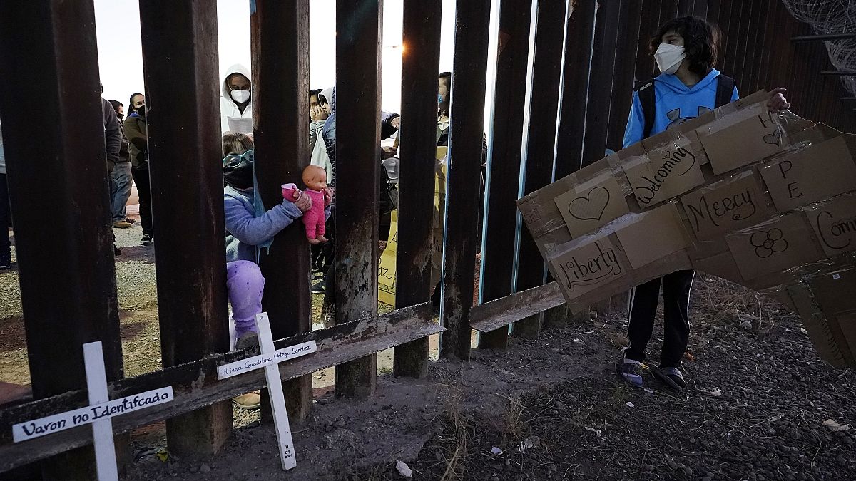 Un niña empuja la muñeca a través de la valla fronteriza con México en Douglas, Arizona.