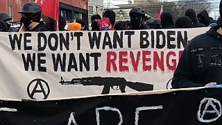 Manifestante com faixa onde se lê: "Não queremos Biden, queremos vingança"