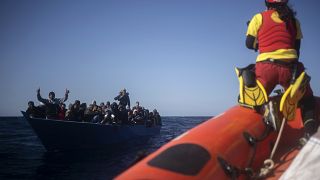 Migrants are assisted by aid workers of the Spanish NGO Open Arms, after fleeing Libya on board a precarious wooden boat in the Mediterranean Sea, Jan. 2, 2021.