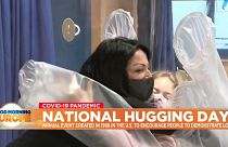 Two people hug through a plastic hugging curtain