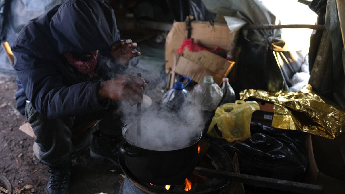 A migrant prepares food in a makeshift camp in a forest outside Velika Kladusa, Bosnia