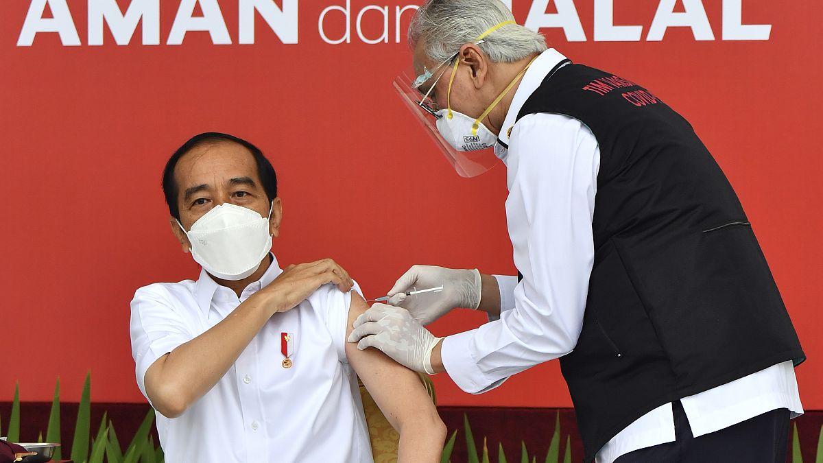 El presidente de Indonesia, Joko Widodo, recibe la vacuna de la covid-19 en el Palacio de Merdeka donde se puede leer una pancarta que dice "Segura y halal".