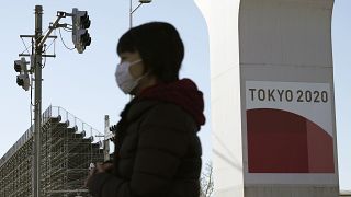 Eine Frau mit Nasen-Mund-Schutz läuft in der Nähe eines olympischen Austragungsortes in Tokio vorbei, 20.01.2021