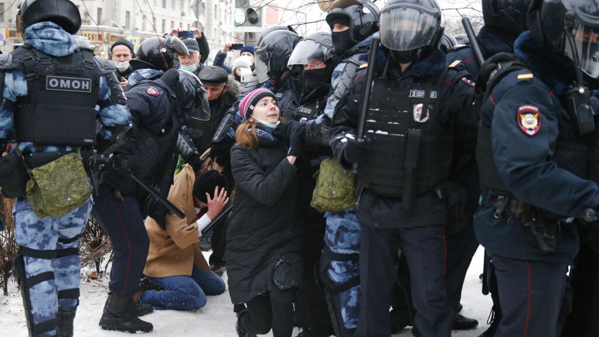 Eine junge Frau bekniet bei der Demonstration in Moskau ein Mitglied der Anti-Terror-Polizei OMON