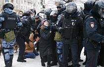 Eine junge Frau bekniet bei der Demonstration in Moskau ein Mitglied der Anti-Terror-Polizei OMON