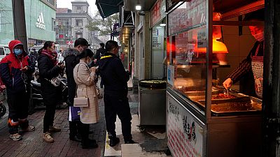 Residentes de Wuhan aguardam para ser entendidos numa banca de comida