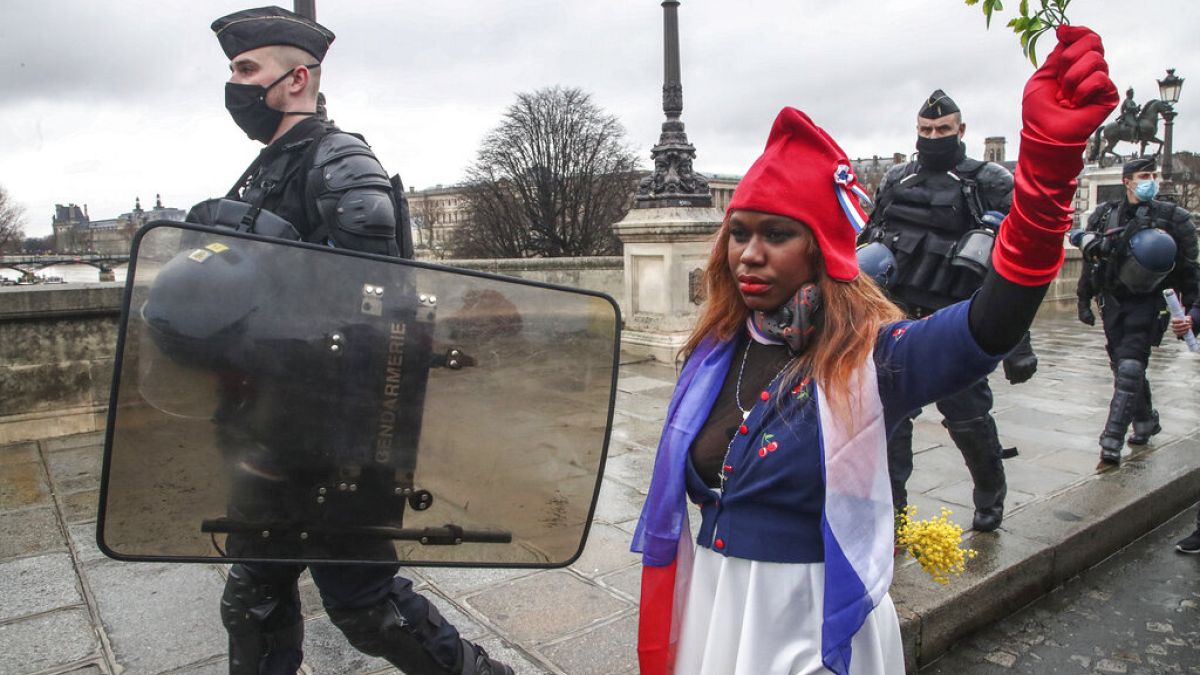 Eine als "Marianne" gekleidete Demonstrantin, dem Symbol der französischen Republik seit 1789, läuft neben Polizeibeamten bei einem "Marsch für die Freiheit", 23.01.21 