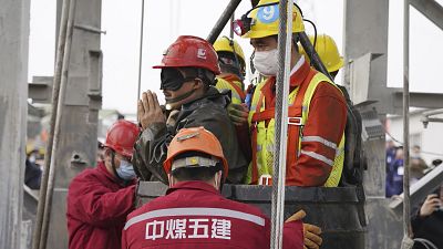 One of twenty-two Chinese miners wearing a black patch is saved from hundreds of metres underground.